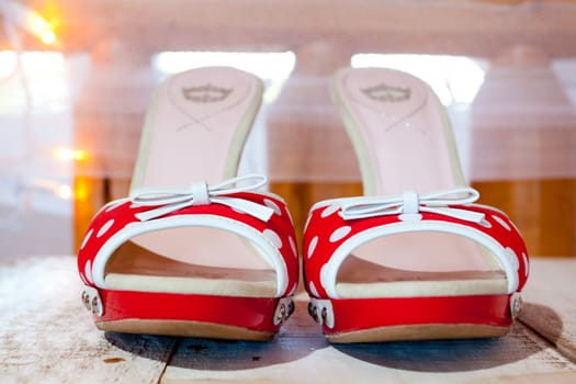 A bride's wedding shoes in red and white with polkadots and heels.