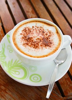 Coffee latte or cappuccino in a cup on wooden background