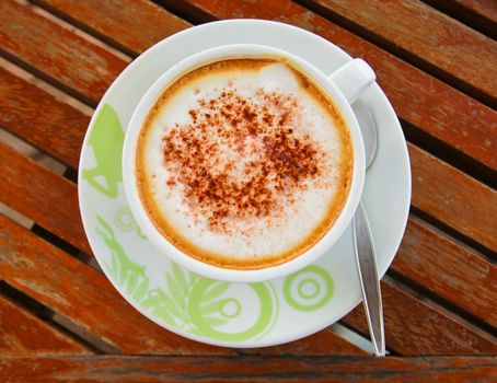 Coffee latte or cappuccino in a cup on wooden background