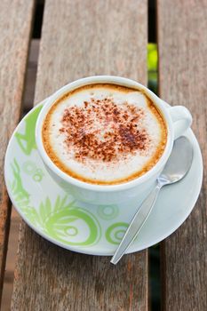 Coffee latte or cappuccino in a cup on wooden background