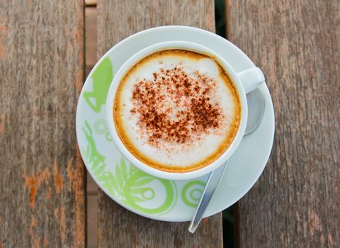 Coffee latte or cappuccino in a cup on wooden background