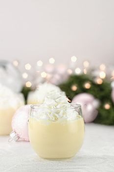 Eggnog with Christmas decor in the background. Shallow depth of field with selective focus on glass in foreground.