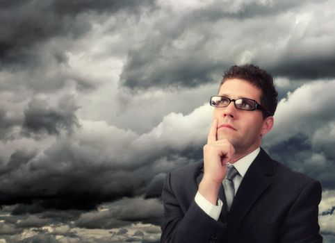 Young businessman against a stormy cloud thinking.Plenty of copy space