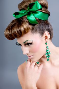 brunette woman with green jewelery and accssesoires on grey background