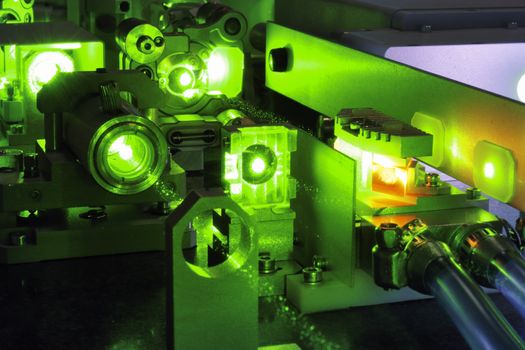 bright green laser light going inside complicate scientific system with cooling hoses inside