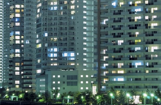 night residential building with many windows illuminated, with street lights below