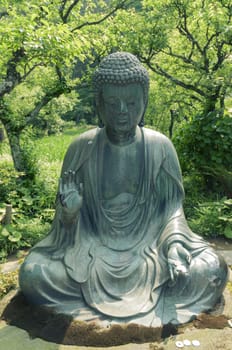 japanese Buddha statue in zen garden environment in Kamakura, Japan; focus on statue
