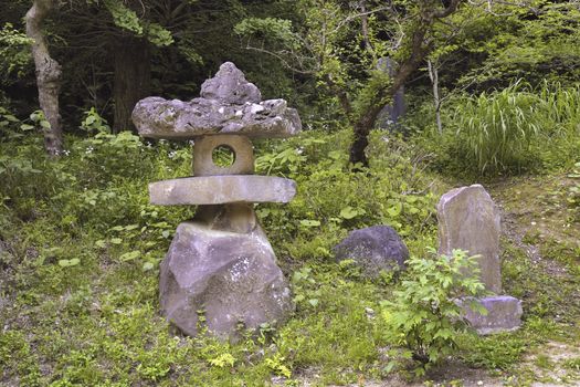 traditional Japanese lantern made from raw volcanic stones in green forest