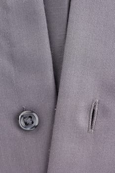 Close-up photograph of a black button on gray material.