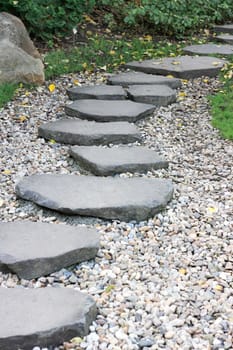 Garden path paved with a natural stone in a autumn garden