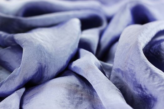 A close up view of the folds and details of shiny violet silk fabric with green beads
