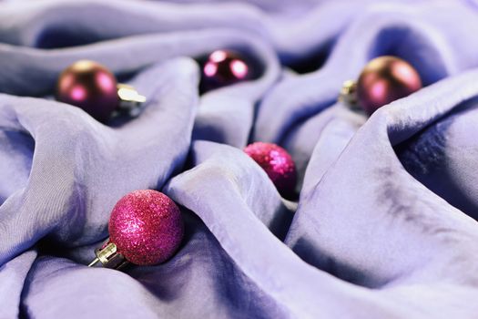 Closeup of several christmas purple baubles on a silk lilac background