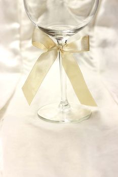 Wineglass with ribbon on silk fair background