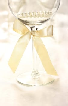 Wineglass with ribbon on silk fair background