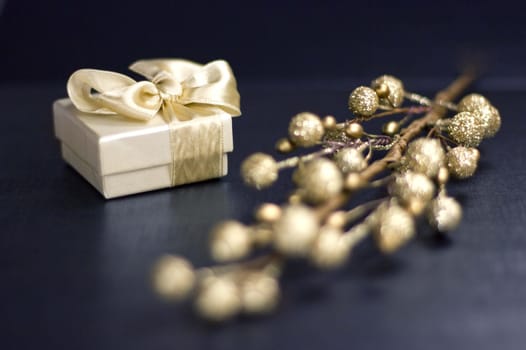 Holiday still life with white gift box and decorative golden glitter branch on a dark blue background