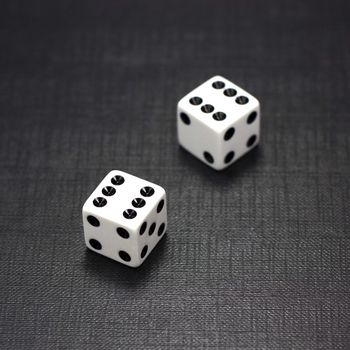 Two white dices on a black background