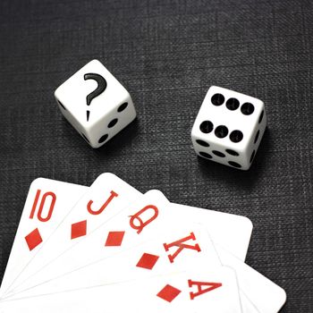 Two white dices and playing cards on a black background