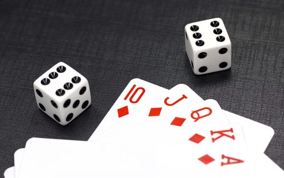 Two white dices and playing cards on a black background