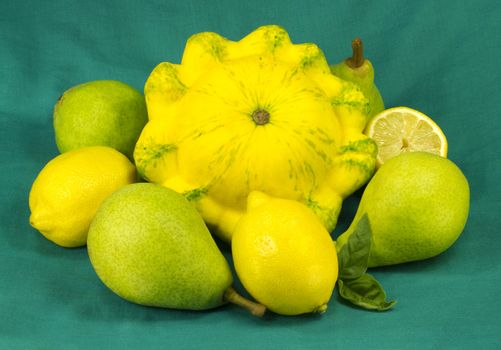 Still life of squash, lemons and pears on a colored fabric background