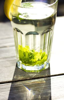 Glass of hot tea with a fresh peppermint and lemon, wooden background