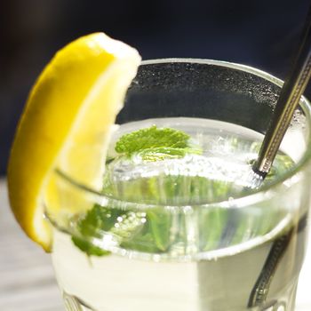 Glass of hot tea with a fresh peppermint and lemon, wooden background