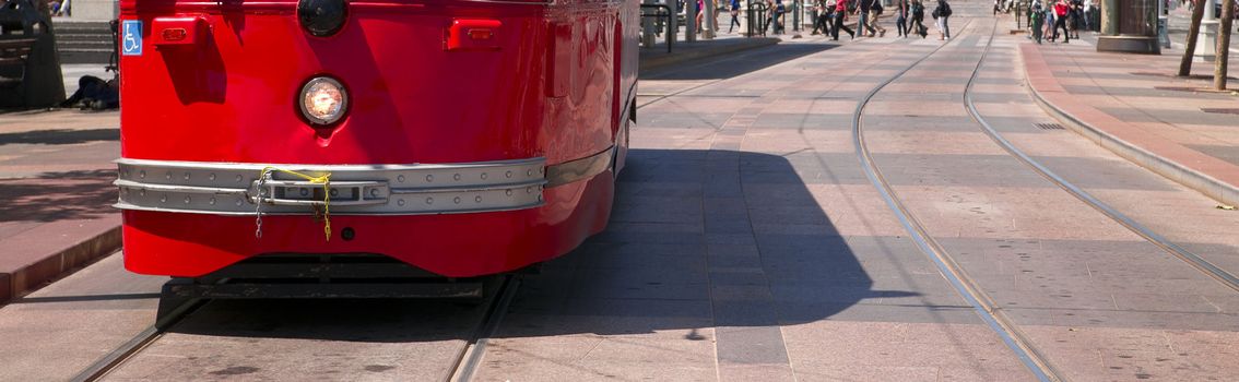 A Red San Francisco Trolley Car moves through the street