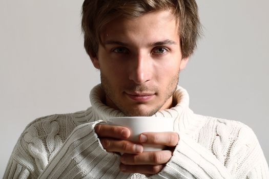 Handsome and beautiful man in white sweater drinking tea