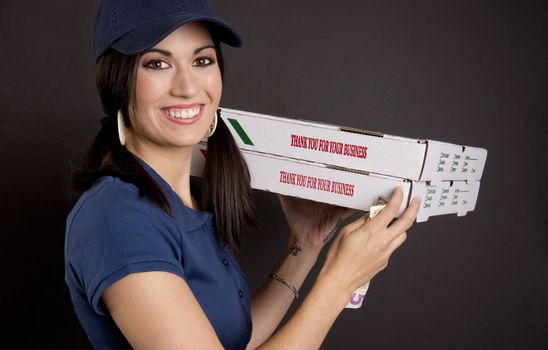 A stunning brunette woman brings pizza and a smile via delivery