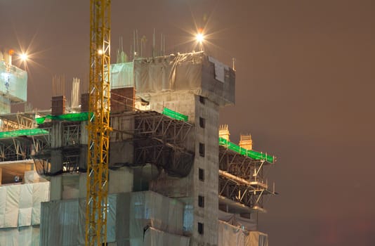 Industrial construction cranes and building at night