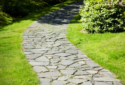 Garden path paved with a natural stone in a autumn garden