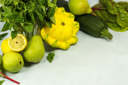 Still life of squashes, basil, pears, lemons and mangold leaves on a background on a fabric background
