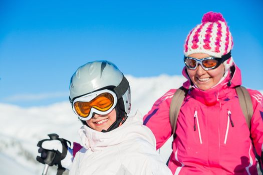 Portrait of happy smiling girl in ski goggles and with her mother, Zellertal, Austria. Focus on the girl