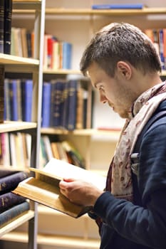 A guy reading a book in a library