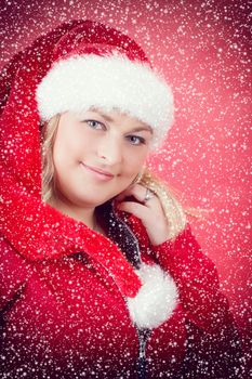 Joyful pretty woman in red santa claus hat smiling on red background