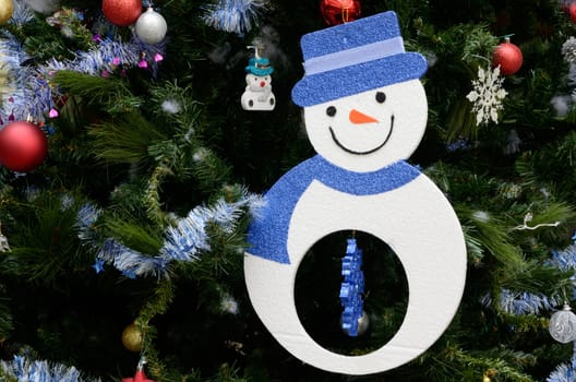 Snow man hanging art on Christmas tree with ornament