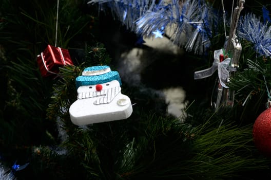 Snow man hanging art on Christmas tree with ornament