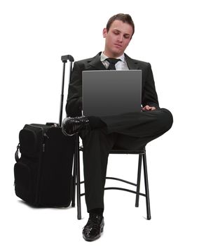 Young traveler businessman working on a laptop next to his suitcase.