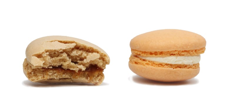 Image of two macarons over a white background. One of them is with a bite missing.