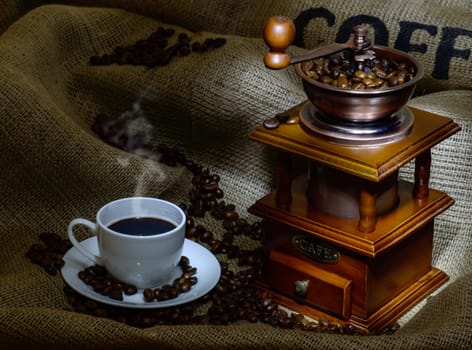 Coffee Mill with beans, cup and burlap. still life