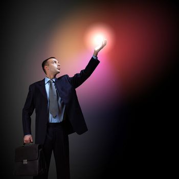 Young successful businessman holding a shining light in his hand as a symbol of success and advancement.