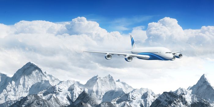 White passenger plane flying in the blue sky above the mountains with snow tops