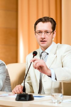 Portrait of a business man holding a microphone and looks ahead