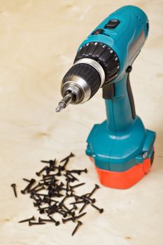 Cordless drill with screws on background