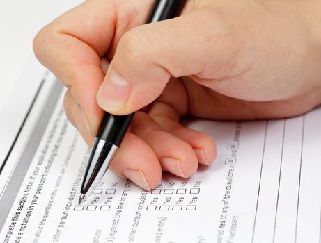 Hand with pen over blank check boxes in application form