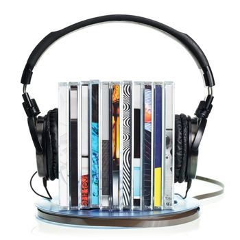 Stack of CDs with HI-Fi headphones on vintage reel of audio tape on white background