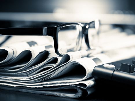 Glasses on stack of newspapers, very shallow focus
