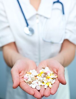 Closeup of doctor holding heap of tablets in her hand, focus on tablets