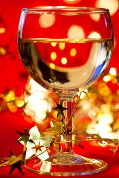 Glass of white wine with star shaped tinsel and lights, very shallow DOF