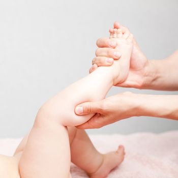 Masseuse massaging little baby girl's foot, shallow focus