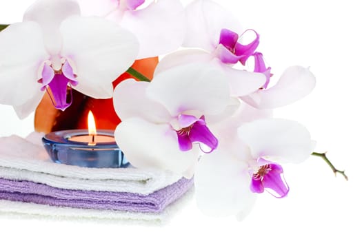 Spa set with white orchid, towels, shell and burning candle on white background